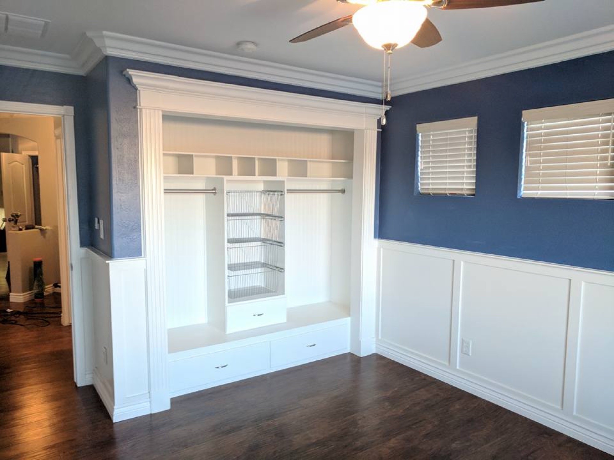 Closet built-in with crown molding, hanging rods, and cubby storage
