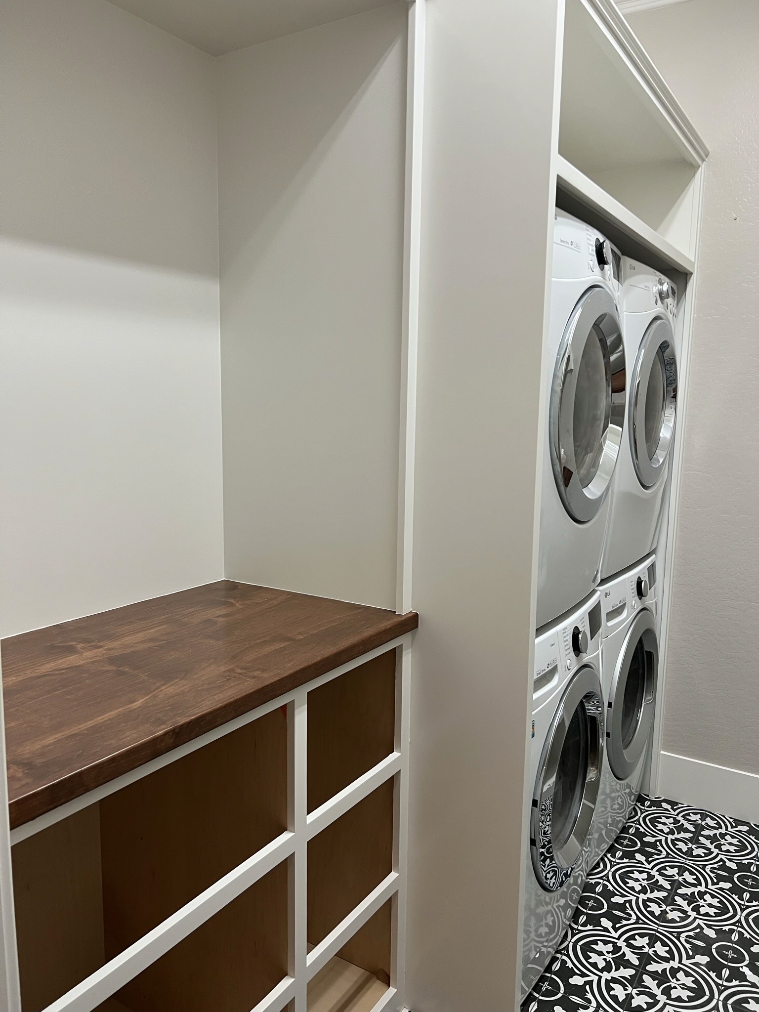 Laundry closet built-in with stacked units and a wood countertop