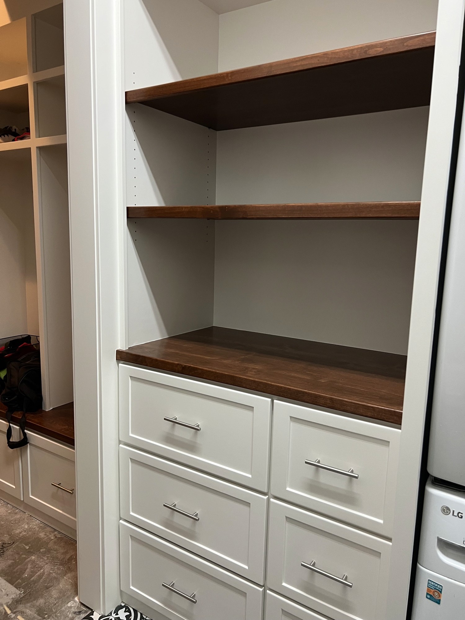 Mudroom storage shelving with stained wood shelves and a drawer bank
