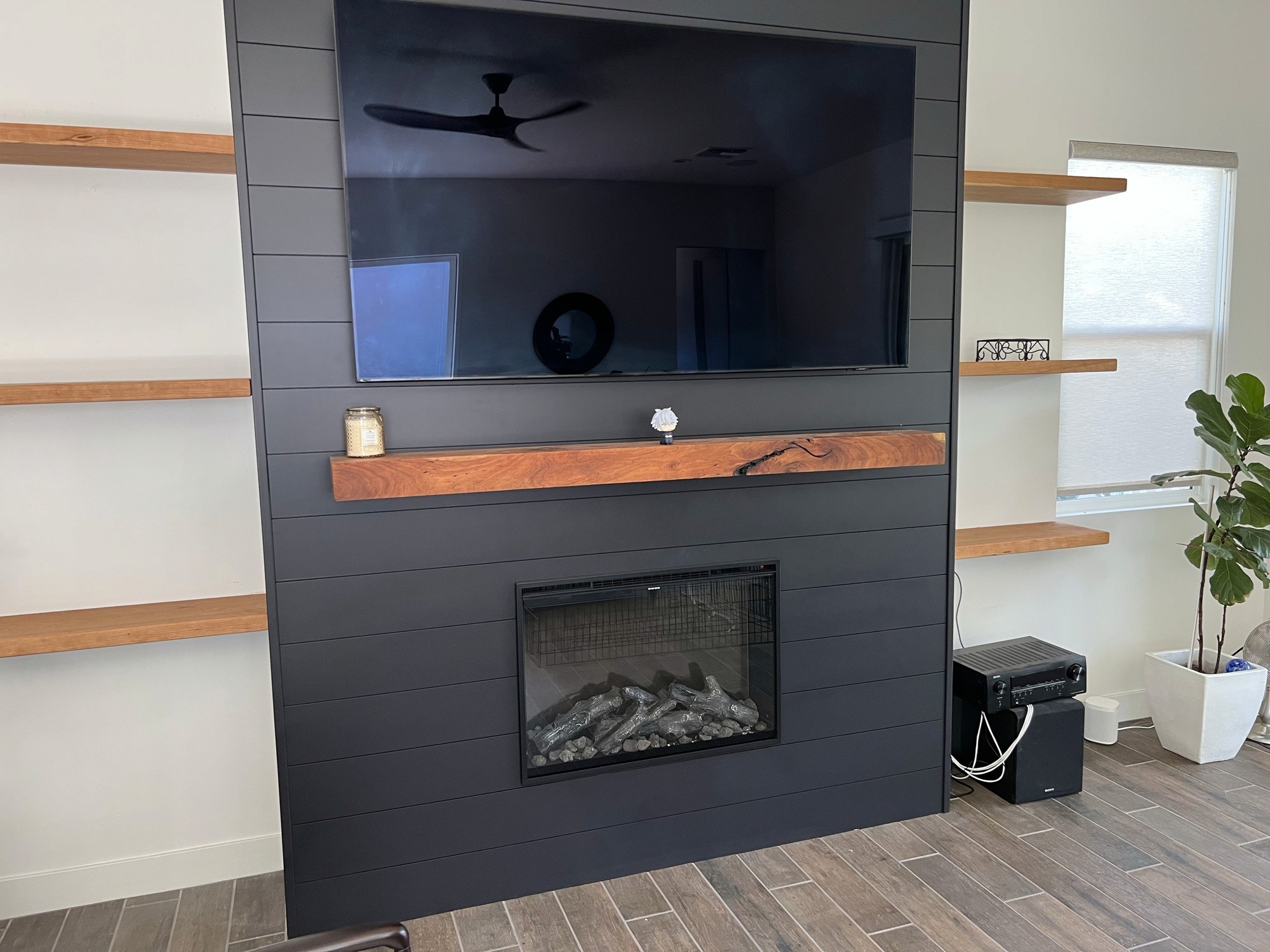 Dark shiplap media wall with a live-edge wood mantel and TV